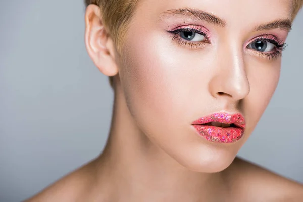 Schöne Frau mit stylischem glitzerndem Make-up mit Blick auf Kamera isoliert auf grau — Stockfoto