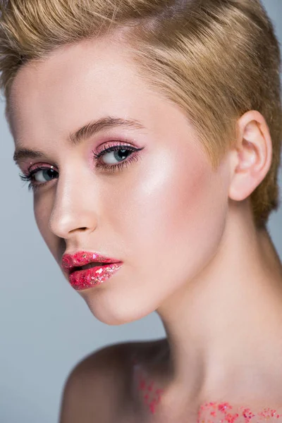 Attractive woman with red lips with glitter looking at camera isolated on grey — Stock Photo