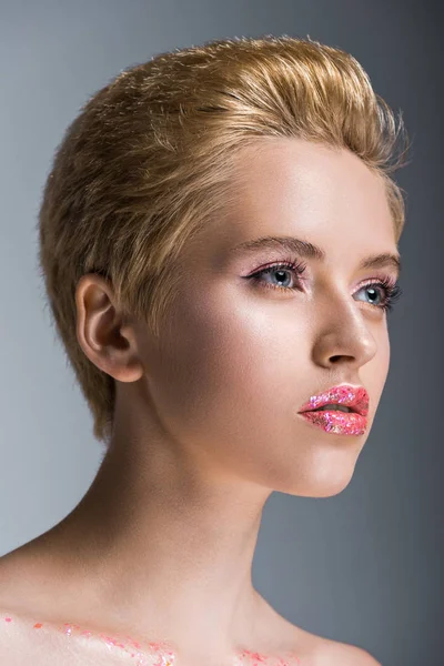 Atractiva mujer con pelo corto y maquillaje mirando hacia otro lado aislado en gris — Stock Photo