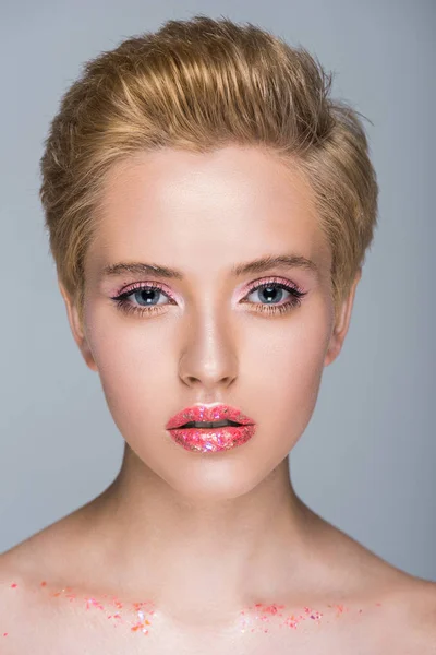 Donna attraente con trucco scintillante e taglio di capelli corto guardando la fotocamera isolata sul grigio — Foto stock