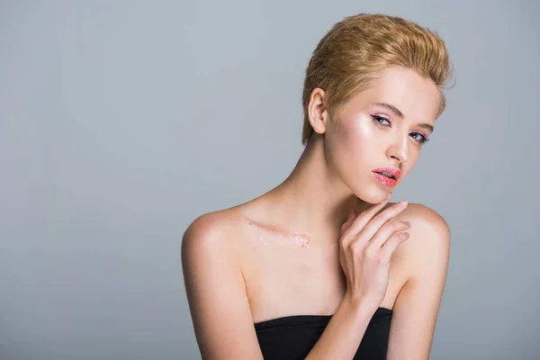 Attraente donna toccare il viso e guardando la fotocamera isolata su grigio — Foto stock