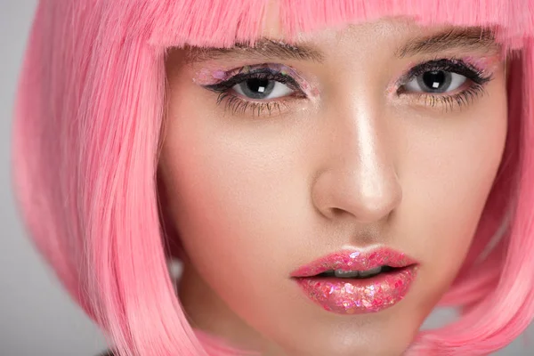 Atractiva mujer con pelo rosa y maquillaje brillante mirando a la cámara - foto de stock