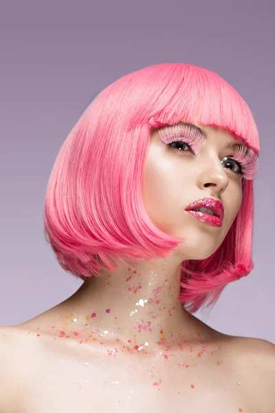 Приваблива жінка з рожевим волоссям і рожевими віями дивиться вгору ізольовано на фіолетовому — стокове фото