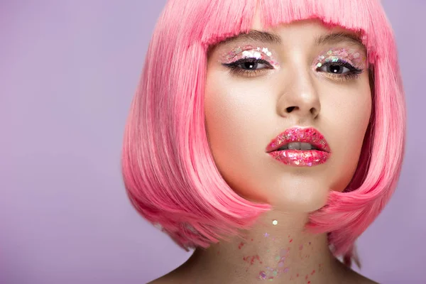 Séduisante femme aux cheveux roses et au maquillage brillant et scintillant regardant la caméra isolée sur violet — Photo de stock