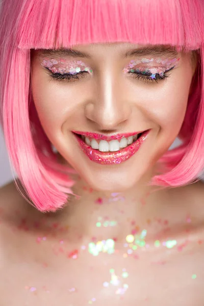 Mujer atractiva sonriente con pelo rosa y brillo en la cara - foto de stock