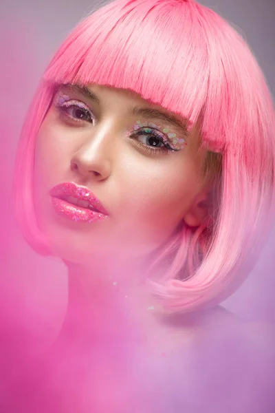 Donna attraente con i capelli rosa e trucco con glitter guardando la fotocamera — Foto stock