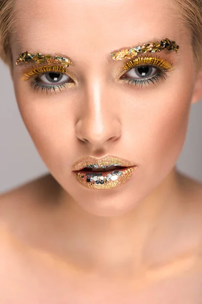 Donna attraente con brillantini dorati sul viso guardando la fotocamera — Foto stock