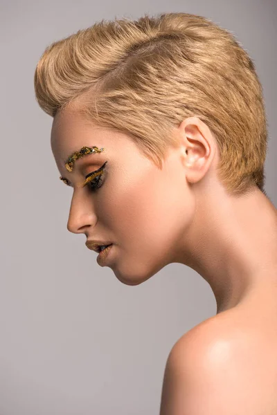 Side view of attractive woman with golden glitter on face isolated on grey — Stock Photo