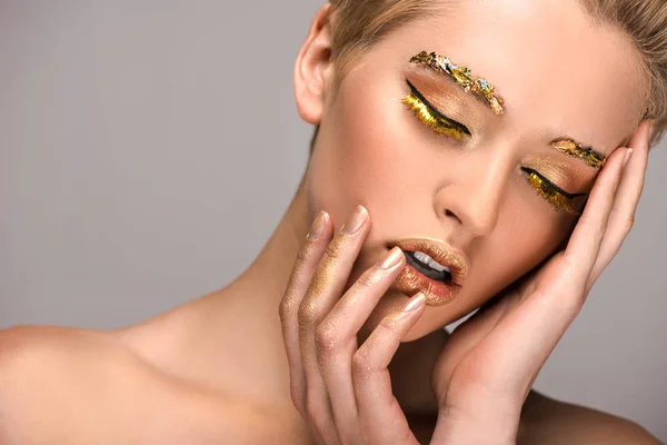 Sensuelle séduisante femme avec maquillage doré toucher visage isolé sur gris — Photo de stock