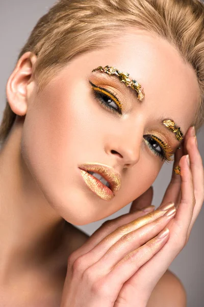 Sensual attractive woman with golden glitter on face looking at camera isolated on grey — Stock Photo