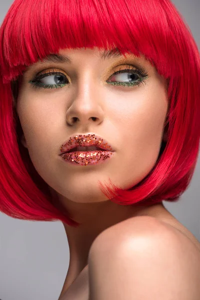 Retrato de mujer hermosa con el pelo rojo y brillo en la cara mirando hacia otro lado aislado en gris - foto de stock