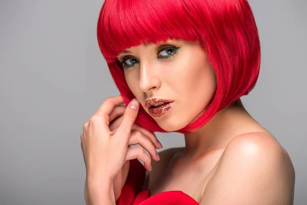 Attractive woman touching red hair and looking at camera isolated on grey — Stock Photo