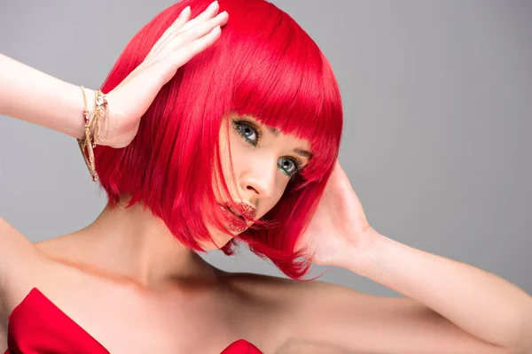 Mulher atraente com cabelo vermelho e brilho no rosto tocando cabeça isolada no cinza — Fotografia de Stock