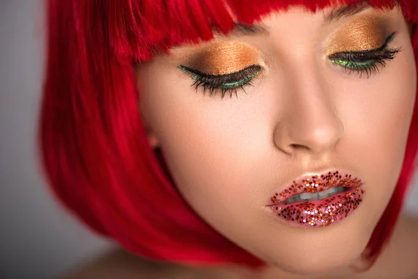 Attractive woman with red hair and glittering makeup looking down — Stock Photo