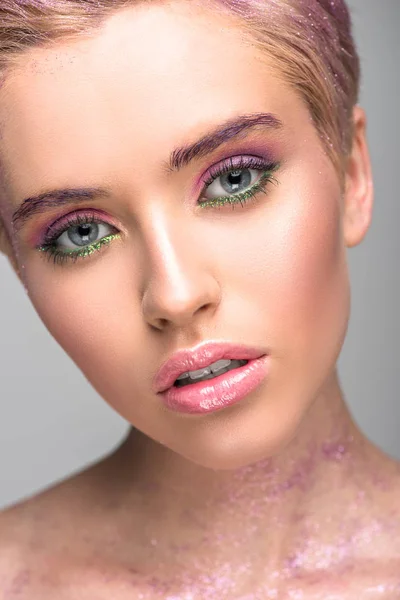 Mulher atraente com maquiagem violeta olhando para a câmera isolada no cinza — Fotografia de Stock