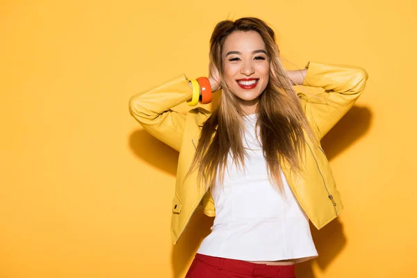 Sorridente asiático fêmea modelo fechamento orelhas por mãos no amarelo fundo — Fotografia de Stock