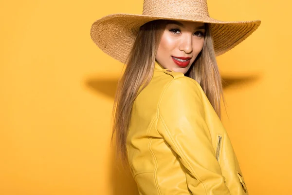 Elegante asiático fêmea modelo em palha posando no fundo amarelo — Fotografia de Stock