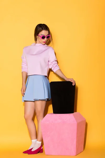 Modelo femenino con estilo en gafas de sol con esmalte de uñas decorativo sobre fondo amarillo — Stock Photo