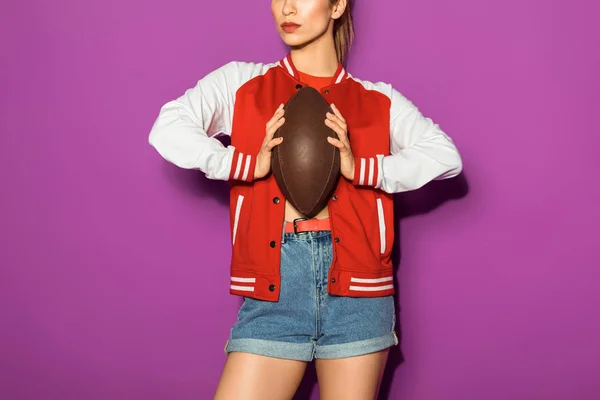 Cropped shot of stylish young woman holding rugby ball isolated on violet — Stock Photo