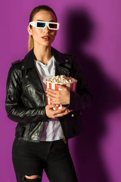 Bela menina elegante em jaqueta de couro e óculos 3d segurando pipoca em violeta — Fotografia de Stock