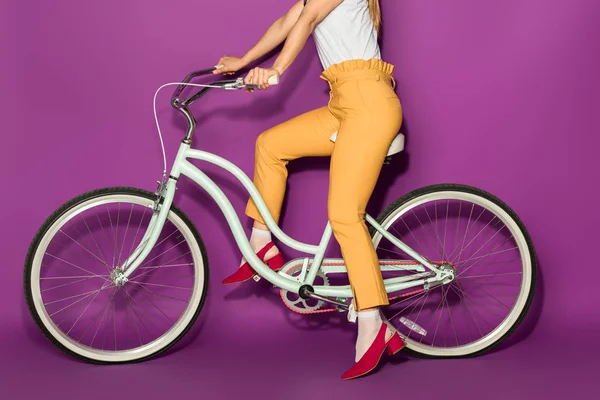Schnappschuss von stilvollem Mädchen auf Fahrrad isoliert auf violett — Stockfoto