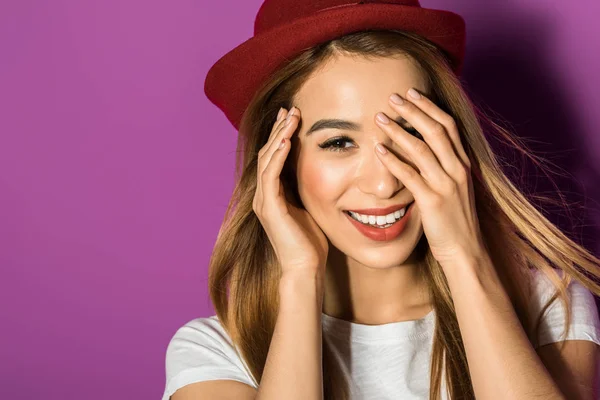 Retrato de bela jovem asiática mulher no chapéu sorrindo para a câmera isolado no violeta — Fotografia de Stock