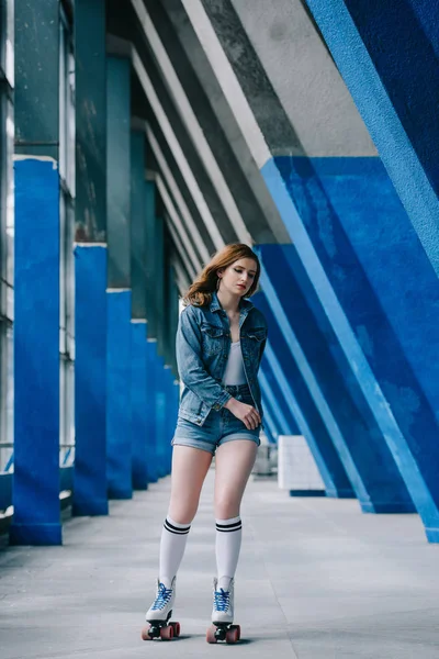 Mujer joven de moda en ropa de mezclilla y calcetines altos patinaje sobre ruedas solo - foto de stock
