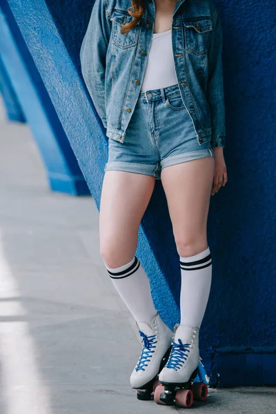 Cropped shot of stylish woman in denim clothes, high socks and retro roller skates — Stock Photo