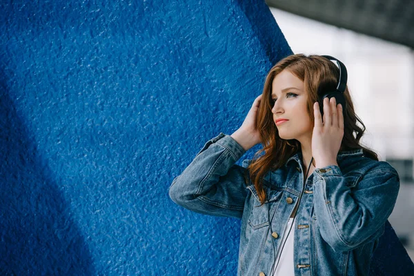 Vista lateral de la joven hermosa mujer escuchando música en auriculares - foto de stock