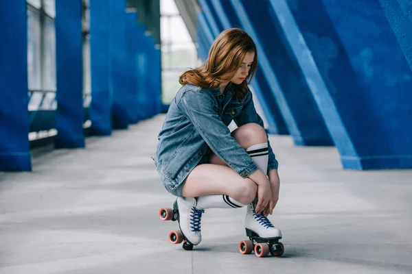 Stylish woman in denim clothes, high socks tying shoelaces on retro roller skates — Stock Photo