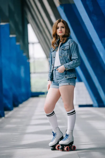 Вид сбоку стильной женщины в джинсовой одежде, высоких носках и ретро роликовых коньках — стоковое фото