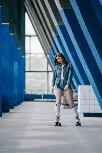 Jeune femme à la mode en vêtements en denim et chaussettes hautes patinage à roulettes seul — Photo de stock