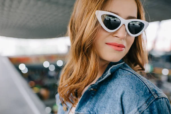 Портрет улыбающейся модной женщины в джинсовой одежде и ретро солнцезащитных очках — стоковое фото