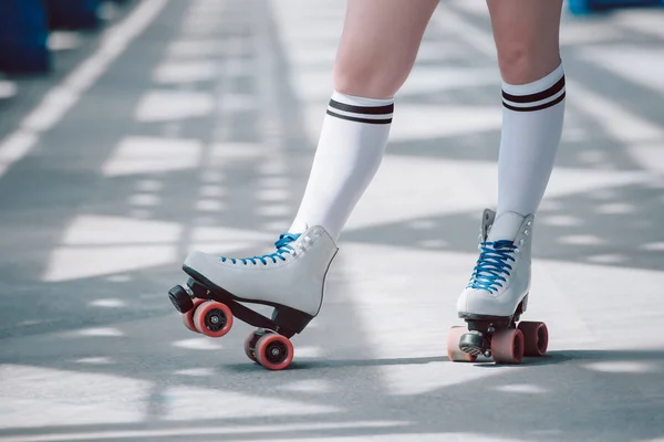 Partial view of woman in white high socks with black stripes and retro roller skates — Stock Photo