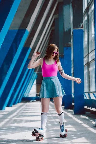 Young woman in stylish clothing and retro sunglasses roller skating alone — Stock Photo