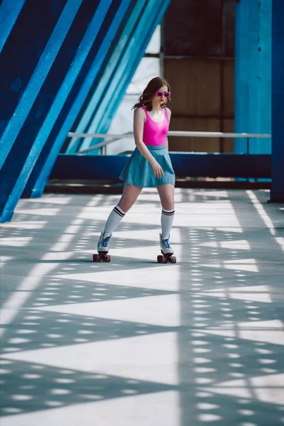 Jeune femme dans des vêtements élégants et des lunettes de soleil rétro roller seul — Photo de stock