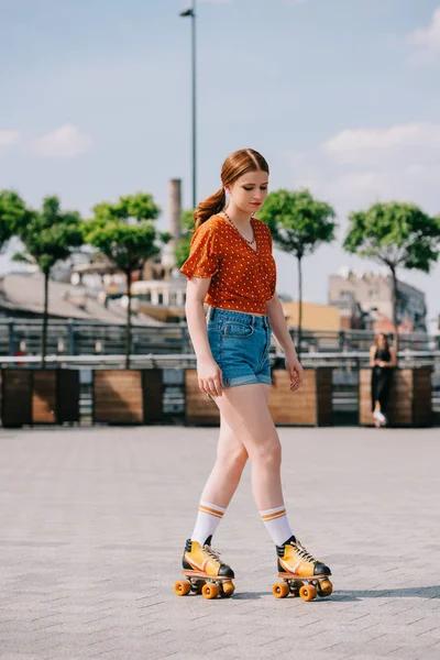 Visão comprimento total da menina atraente em calções jeans patinação rolo na rua — Fotografia de Stock