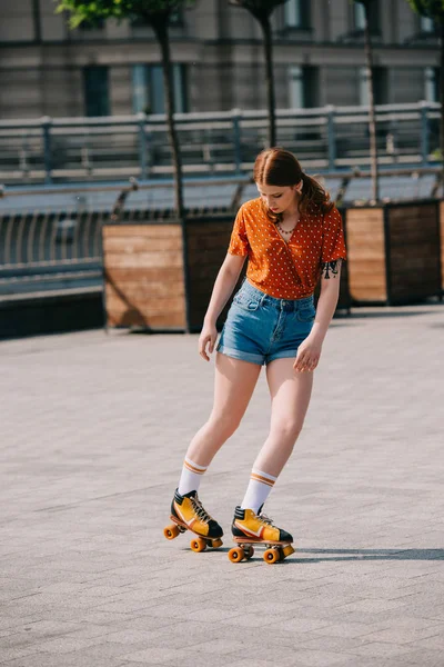 Hermosa chica en pantalones vaqueros patinaje sobre ruedas en la calle - foto de stock