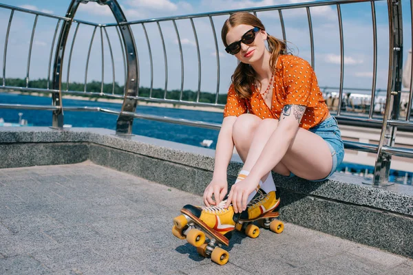 Hermosa chica en gafas de sol con patines vintage y mirando a la cámara - foto de stock