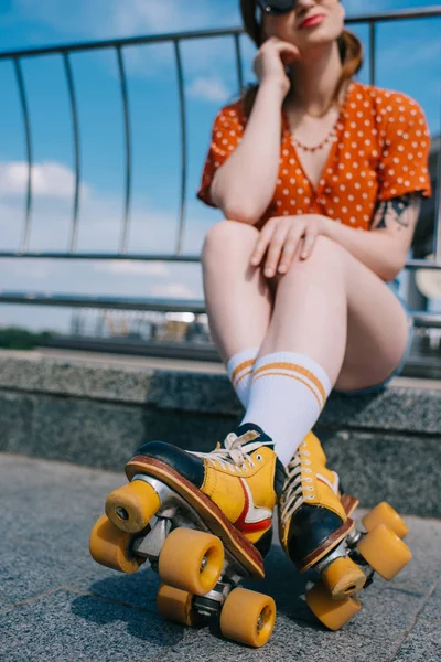 Tiro cortado de menina elegante em patins vintage sentado na rua — Fotografia de Stock