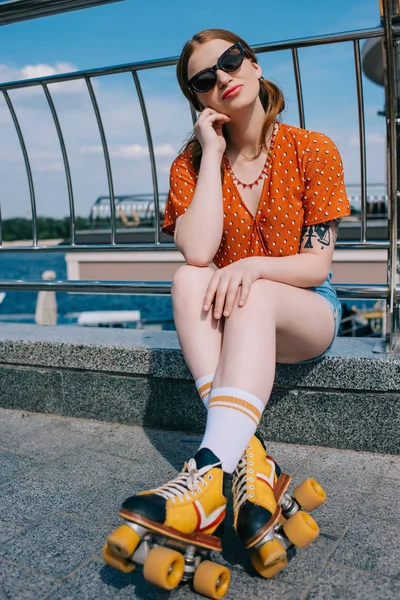 Bela menina elegante em óculos de sol vestindo patins e sorrindo para a câmera na rua — Fotografia de Stock