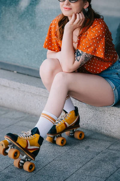 Cropped shot of smiling stylish woman in roller skates sitting on stairs — Stock Photo