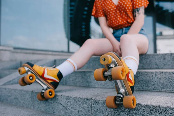 Cropped shot of stylish young woman in roller skates sitting on stairs — Stock Photo