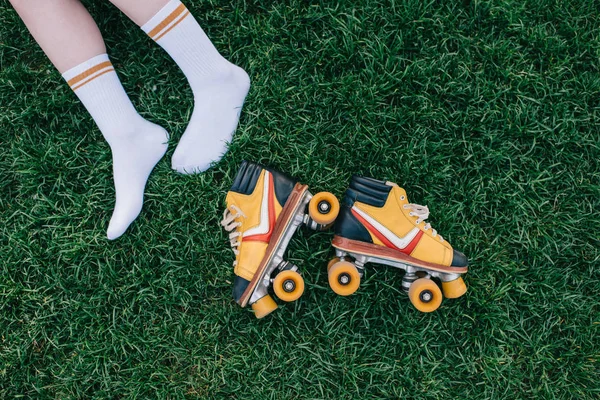 Cropped shot of female legs in socks and vintage roller skates on green grass — Stock Photo