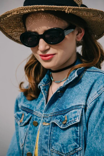 Портрет красивой улыбающейся девушки в солнцезащитных очках, шляпе и джинсовой куртке — стоковое фото