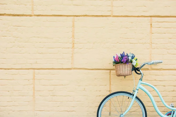 White bicycle with beautiful flowers in basket near wall — Stock Photo