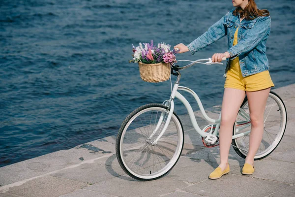 Обрізаний знімок дівчини з велосипедом, що стоїть на набережній біля річки — стокове фото