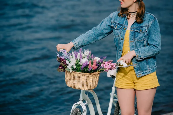 Cropped shot of girl standing with bicycle and looking at river — Stock Photo