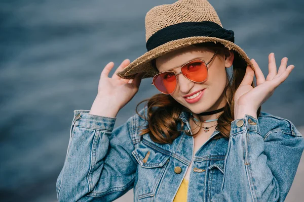 Porträt einer schönen, stylischen jungen Frau mit Hut und Sonnenbrille, die im Freien in die Kamera lächelt — Stockfoto