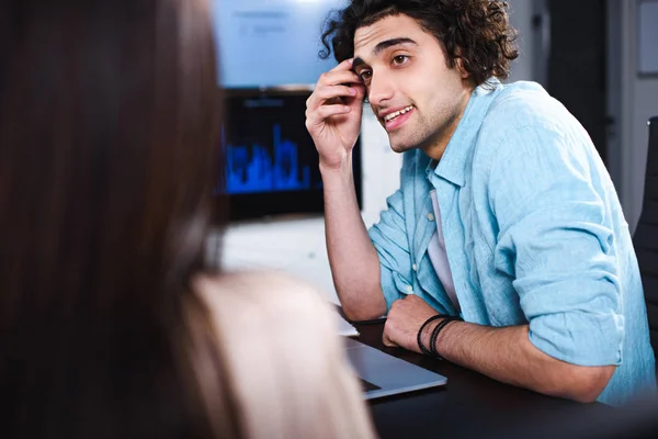 Молодий бізнесмен сидить за столом з ноутбуком і розмовляє з партнером в сучасному офісі — стокове фото